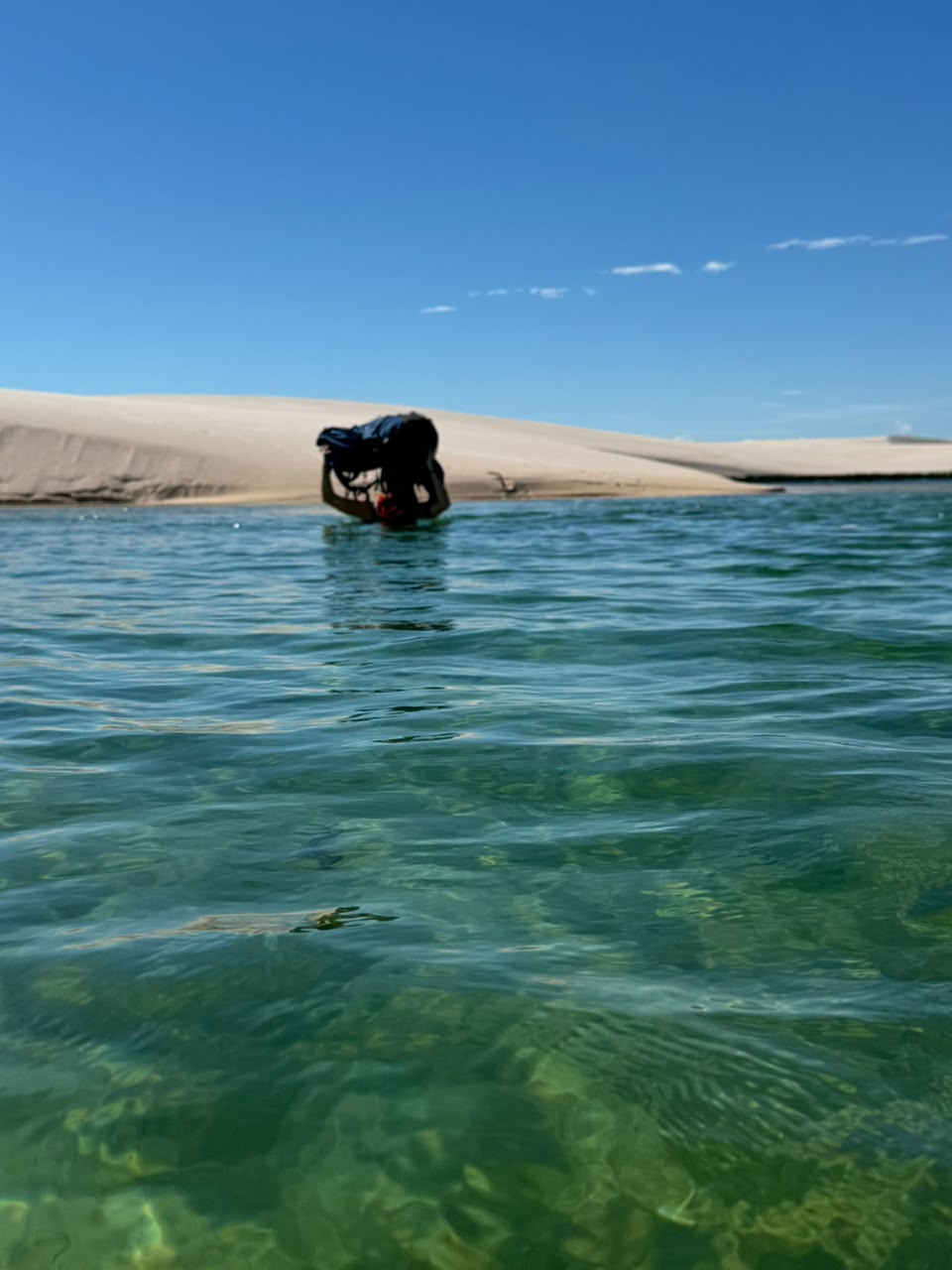 Pessoa atravessando lagoa com a mochila na cabeça